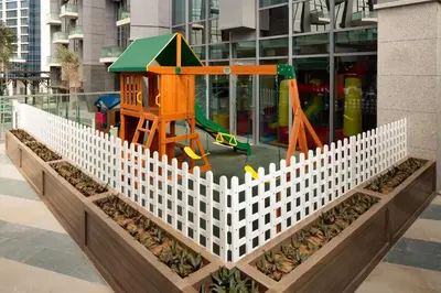 a playground in a white fence in front of a building at Millennium Atria Business Bay in Dubai