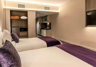 a hotel room with two beds and a flat screen tv at Leva Hotel and Suites, Opposite Downtown in Dubai