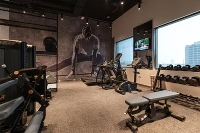 a gym with exercise equipment and a large screen at Studio One Hotel in Dubai