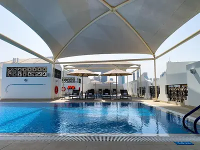 a large swimming pool with tables and umbrellas at Al Khoory Executive Hotel, Al Wasl in Dubai