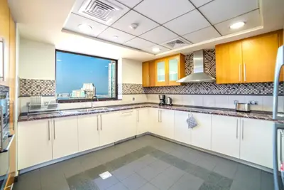 a kitchen with white cabinets and a large window at Royal Beach Residence in Dubai