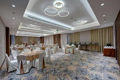 a banquet hall with white tables and white chairs at The S Hotel Al Barsha in Dubai