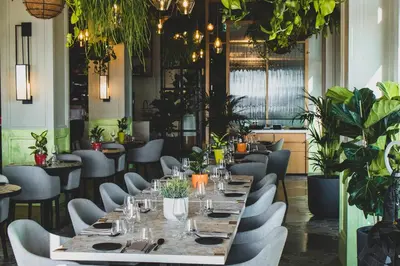 a dining room with a long table and chairs and plants at Vida Creek Harbour in Dubai