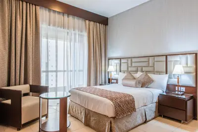 a hotel room with a bed and a chair at SUHA JBR Hotel Apartments in Dubai