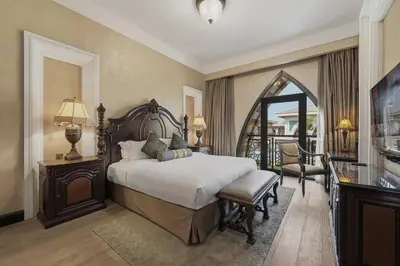 a bedroom with a large bed and a balcony at Zabeel Saray Royal Residences Lagoon Villa in Dubai
