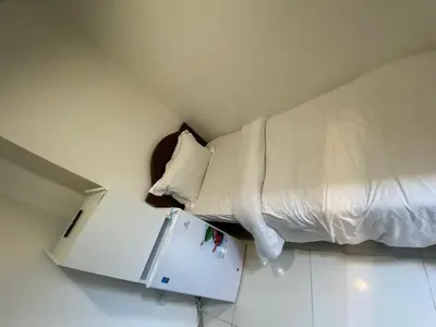 a bed and a refrigerator in a small room at Budget Rooms With Private Bathroom for 'girls' only in Dubai, Marina in Dubai