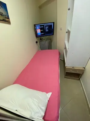 a hospital room with a pink bed and a tv at Small Budget Rooms for 'girls' only in Dubai, Marina in Dubai