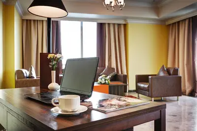 a laptop on a wooden table with a cup of coffee at Abidos Hotel Apartment Dubai Land in Dubai