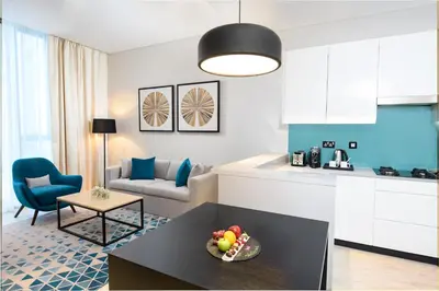 a kitchen and a living room with a couch and a table at Millennium Al Barsha in Dubai