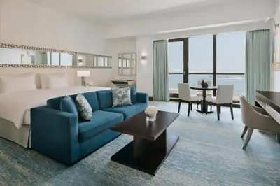 a hotel room with a bed and a blue couch at JA Ocean View Hotel, Jumeirah Beach Dubai in Dubai