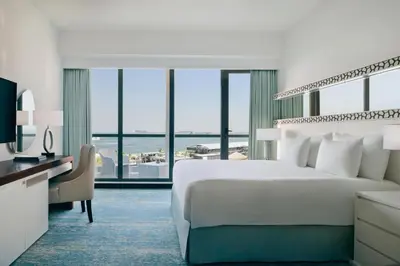 a bedroom with a bed and a desk and a large window at JA Ocean View Hotel, Jumeirah Beach Dubai in Dubai