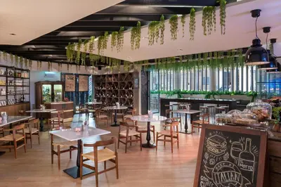 a restaurant with tables and chairs and windows at JA Ocean View Hotel, Jumeirah Beach Dubai in Dubai