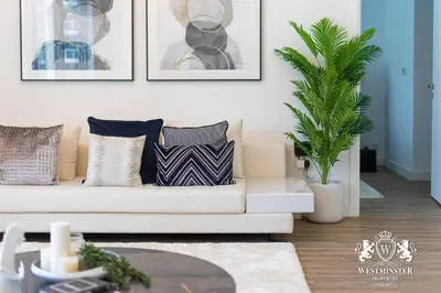 a living room with a white couch and a palm tree at Westminster Burj Residences in Dubai