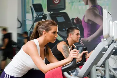a man and woman riding on a treadmill in a gym at Millennium Plaza Downtown Suites in Dubai