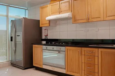 a kitchen with wooden cabinets and a stainless steel refrigerator at Roda Al Murooj Residences in Dubai