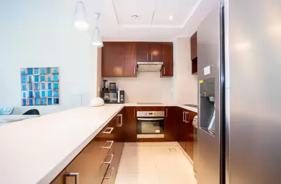 a kitchen with wooden cabinets and a stainless steel refrigerator at New Arabian -Panorama 2 BR Full Golf course View in Dubai