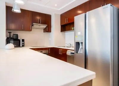 a kitchen with wooden cabinets and a stainless steel refrigerator at New Arabian -Panorama 2 BR Full Golf course View in Dubai