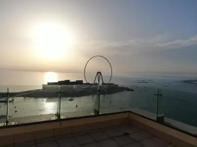 a ferris wheel on top of a building with the sunset at Jbr penthouse with terrace pool in Dubai