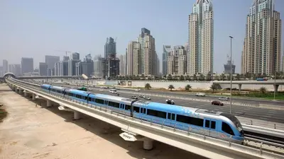 a blue and white train on a bridge over a highway at Deluxe Studio for Rent at Marina View Towers in Dubai