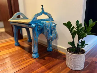 a blue stool sitting on a wooden floor next to a plant at AUBERGE Luxury 2BR Full Burj Khalifa and Fountain View in Dubai