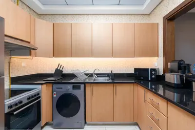 a kitchen with a washing machine and a sink at BLVD - Spacious Fully Equipped Luxury Residences - Dubai - JVC in Dubai