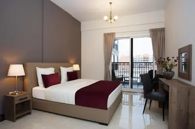 a bedroom with a bed and a desk and a balcony at BLVD - Spacious Fully Equipped Luxury Residences - Dubai - JVC in Dubai