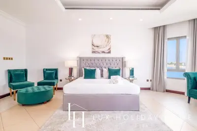 a bedroom with a bed and two green chairs at LUX - The Ocean Pearl Villa in Dubai