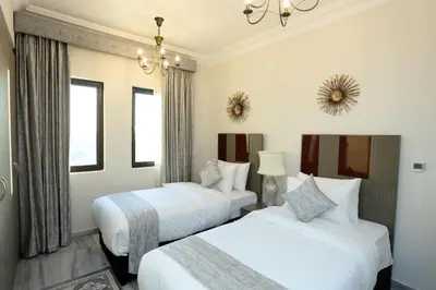 a bedroom with two beds and a chandelier at Marbella Holiday Homes in Dubai