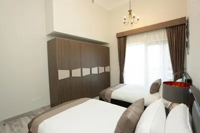 a hotel room with two beds and a window at Marbella Holiday Homes in Dubai