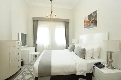 a white bedroom with a bed and a window at Marbella Holiday Homes in Dubai