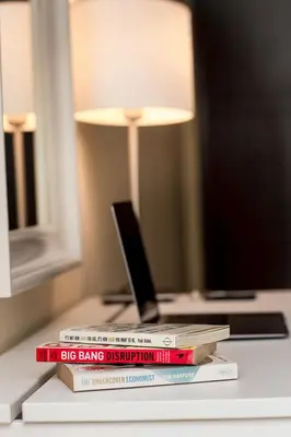 a stack of books sitting on a table with a lamp at Prime Retreats- Downtown Dubai in Dubai
