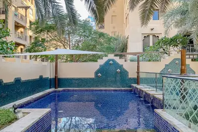a swimming pool with an umbrella next to a building at Frank Porter - Reehan 5 in Dubai