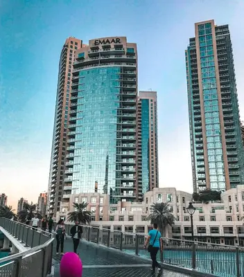 people walking on a bridge in a city with tall buildings at Elite Royal Apartment - Full Burj Khalifa & Fountain View - Deluxe in Dubai