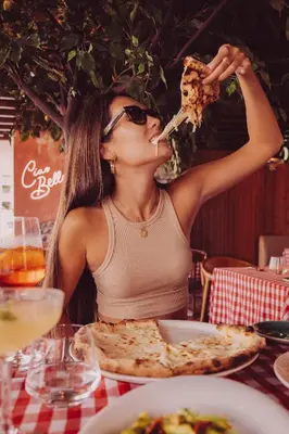 a woman sitting at a table eating a slice of pizza at FIVE Jumeirah Village in Dubai