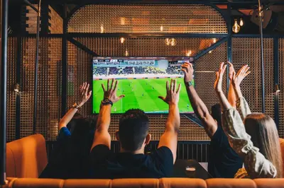 a group of people watching a soccer game on a television at FIVE Jumeirah Village in Dubai