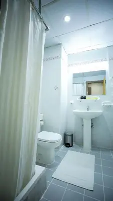 a white bathroom with a sink and a toilet at Green House Hotel Suites & Apartment in Dubai