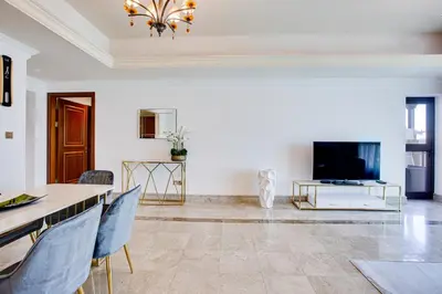 a living room with a television and a table and chairs at South & North Residence Palm Jumeirah in Dubai