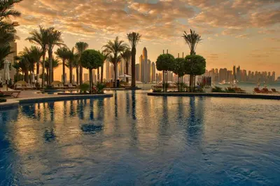 a large swimming pool with palm trees and a city at South & North Residence Palm Jumeirah in Dubai