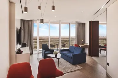 a living room with a blue couch and red chairs at JA Lake View Hotel, Dubai in Dubai