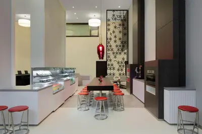 a kitchen with a table and some red stools at Hyatt Place Dubai Jumeirah Residences in Dubai