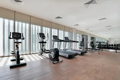 a gym with several treadmills and cardio machines at Millennium Executive Apartments Mont Rose in Dubai