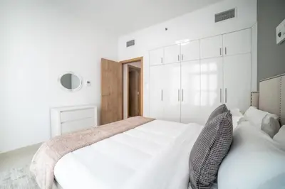 a white bedroom with a large white bed with two pillows at Continental Tower, Dubai Marina - Luton Vacation Homes in Dubai