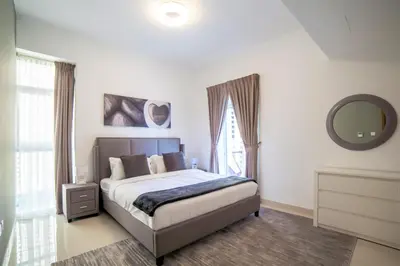 a bedroom with a bed with a mirror and a window at Continental Tower, Dubai Marina - Luton Vacation Homes in Dubai