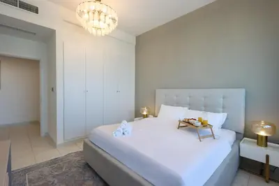 a bedroom with a large white bed and a chandelier at Elite Duplex Penthouse Steps from Metro & Marina in Dubai