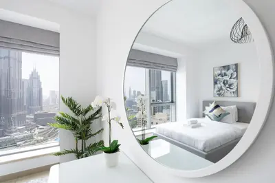 a white bedroom with a bed and a mirror at Spectacular 2BR with Burj Khalifa and Fountain View in Dubai