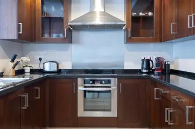 a kitchen with wooden cabinets and a stove top oven at Spectacular 2BR with Burj Khalifa and Fountain View in Dubai