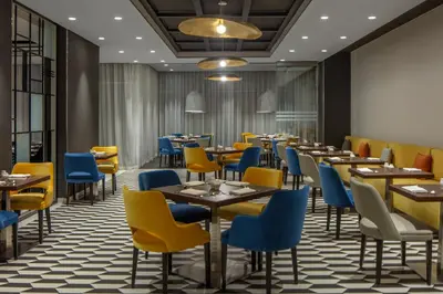 a restaurant with yellow and blue chairs and tables at Hyatt Place Dubai Jumeirah in Dubai