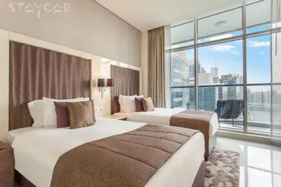 a hotel room with two beds and a large window at Staycae Bay's Edge in Dubai