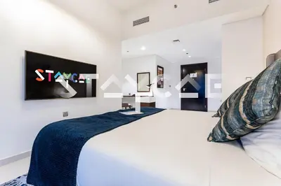 a white bedroom with a bed and a sign on the wall at Staycae Avanti in Dubai