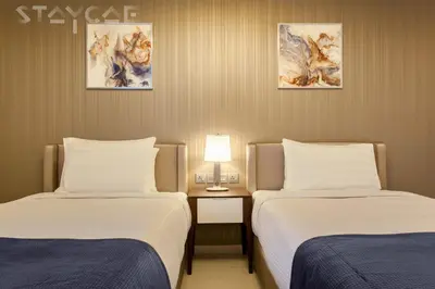a hotel room with two beds and a table with a lamp at Staycae Avanti in Dubai